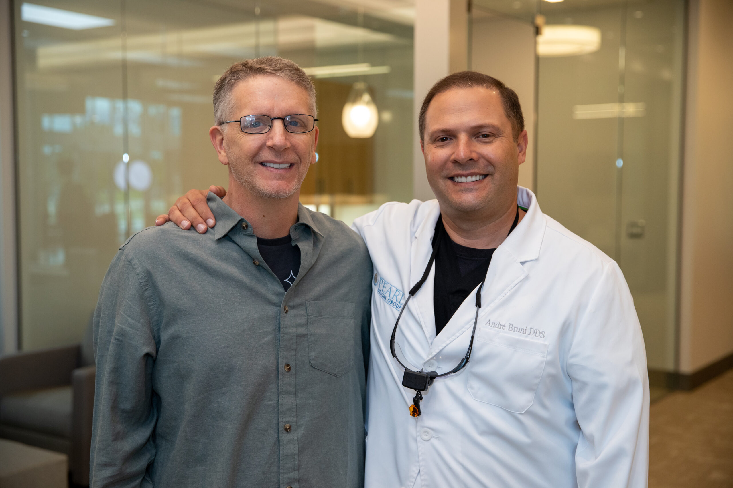 Dr. Bruni and a patient smiling together in Dr. Bruni's office after his full mouth dental implant procedure.