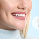Young woman with implanted teeth on color background, closeup